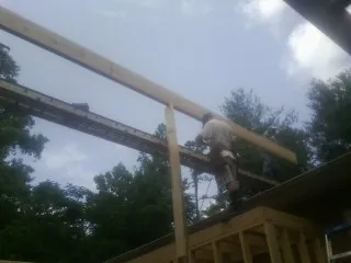 Carpenter setting a ridge beam over a new addition frame — Ice Dam Removal by Roofing Brothers in Carlock