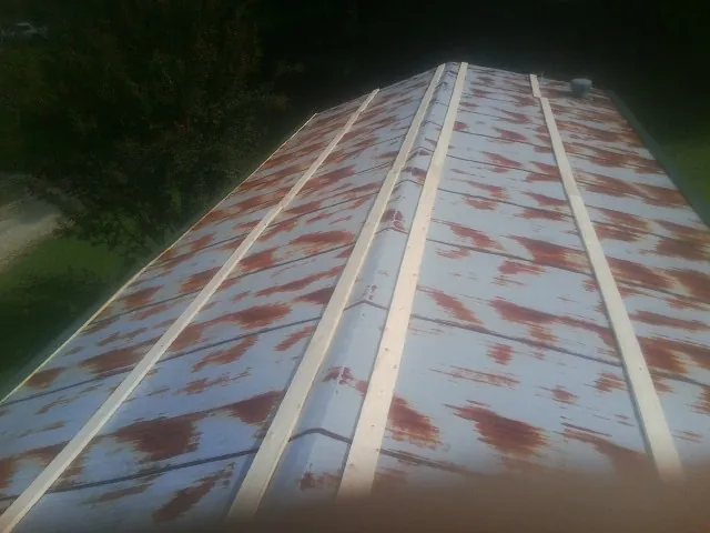 Rusted metal roof panels with new wood purlins before replacement — Storm Damage Roof Repair in Carlock by Roofing Brothers