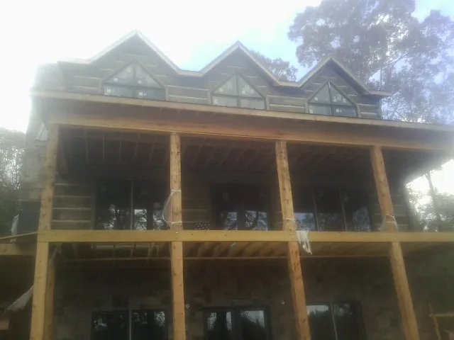 Dormers and porch framing on a large log home under construction — Roof Coating work by our crew in Carlock