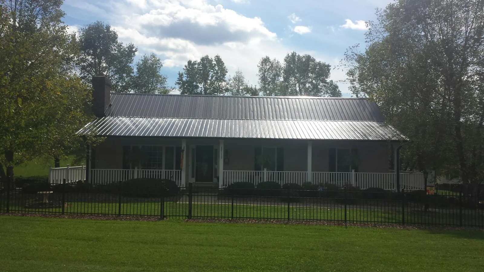 Gray metal roof on a brick ranch with a full width front porch — Gutter Guard Installation work by our crew in Carlock