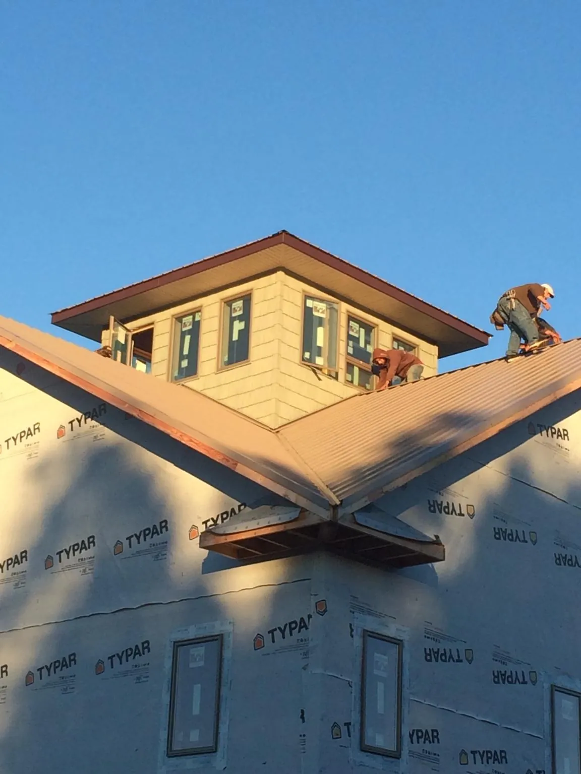 Roofers working around a rooftop cupola on a new metal roof at sunset — Roof Waterproofing in Carlock by Roofing Brothers